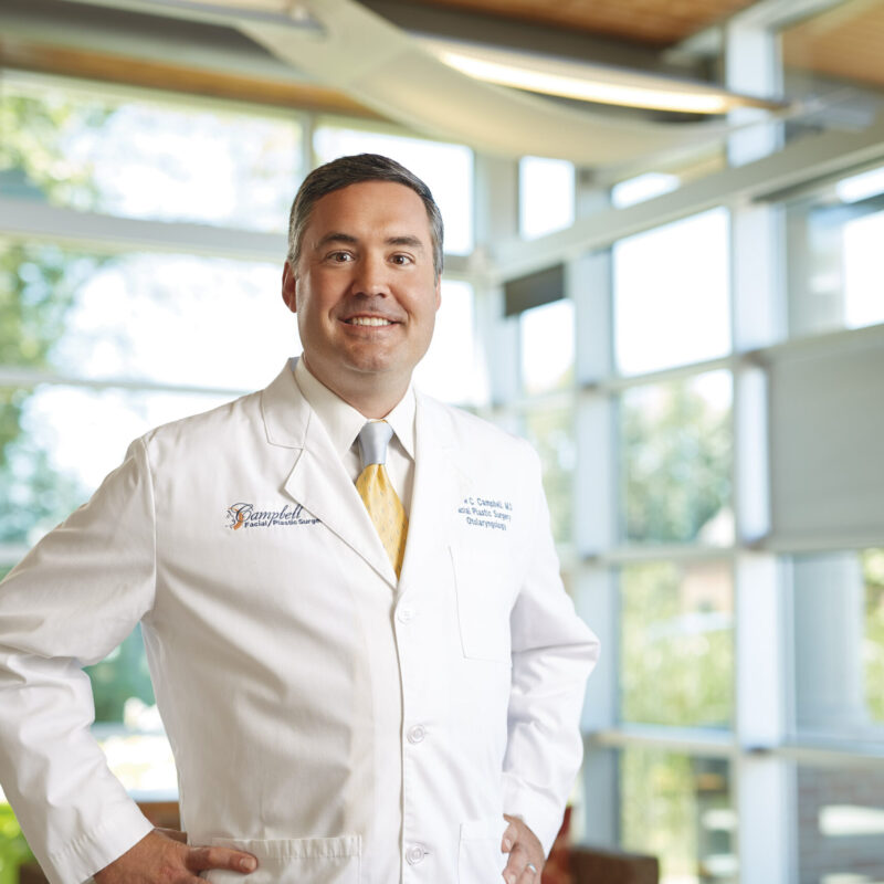 Dr. Andrew Campbell smiling and posing in front of windows at Quintessa