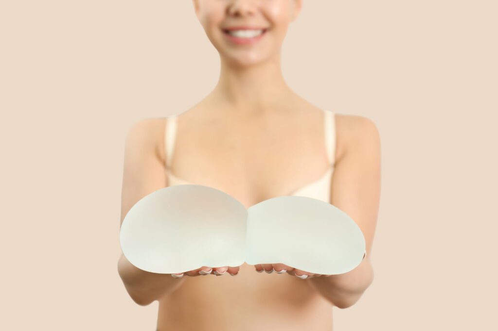 Woman holding silicone breast implants for augmentation.