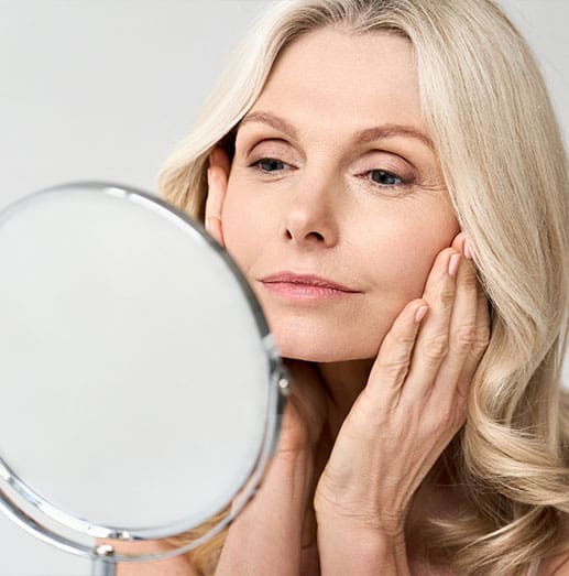 Woman looking in a mirror after dermal fillers in brookfield at Quintessa.