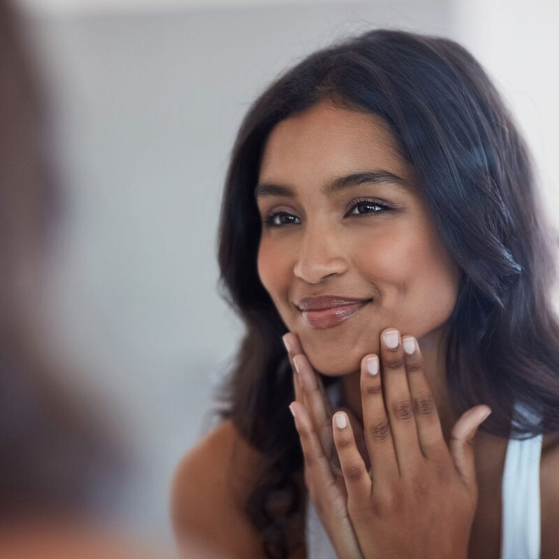 woman looking in the mirror after getting dermal fillers