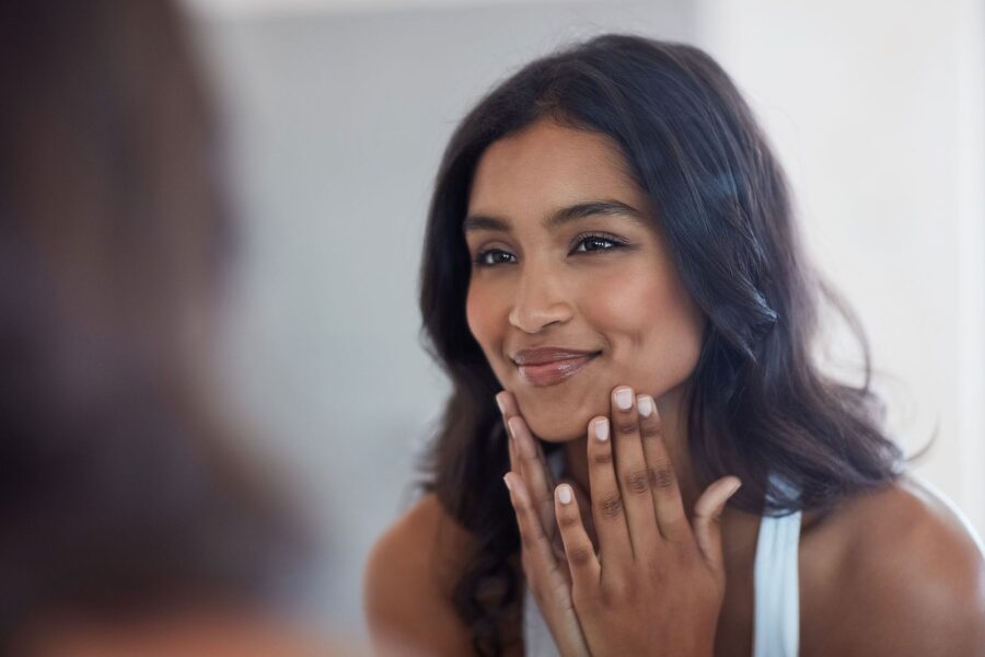 woman looking in the mirror after getting dermal fillers